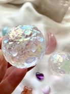 Close-up of Angel Aura Full Moon sphere with soft crystal background on white silk — glowing lunar texture with ethereal rainbow sheen.