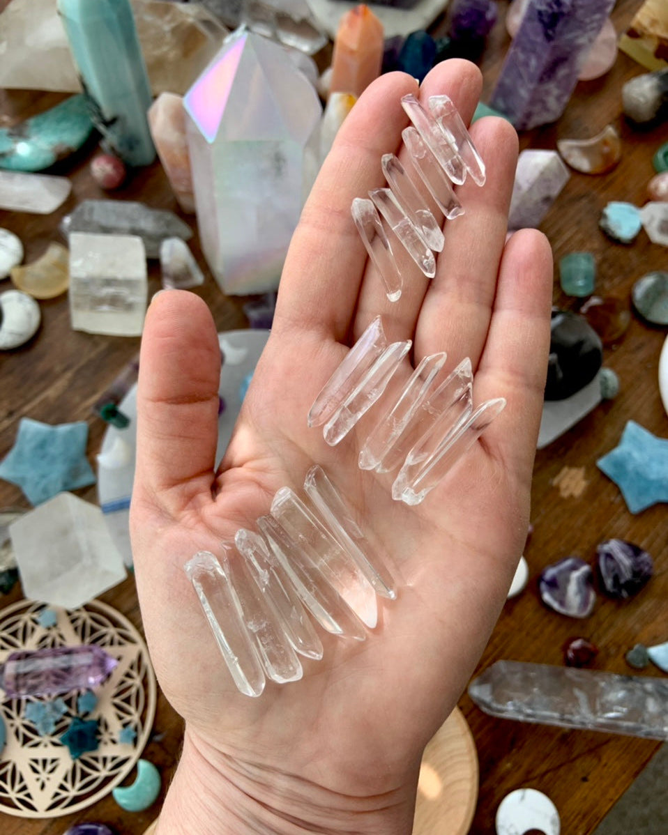 Small clear quartz points held in hand showing natural variations and mineral inclusions in raw quartz