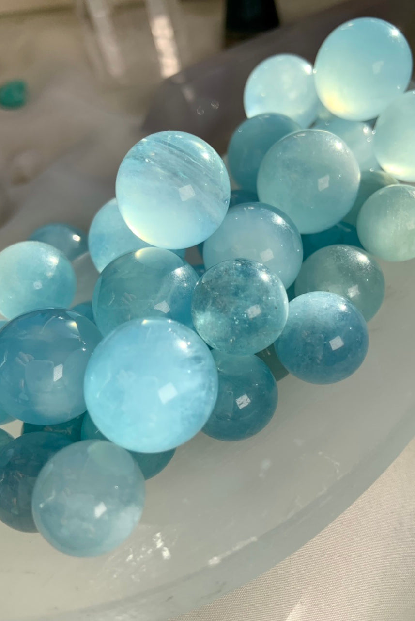 Mini aquamarine sphere crystal balls in soft ocean blue tones with natural banding and glossy polish