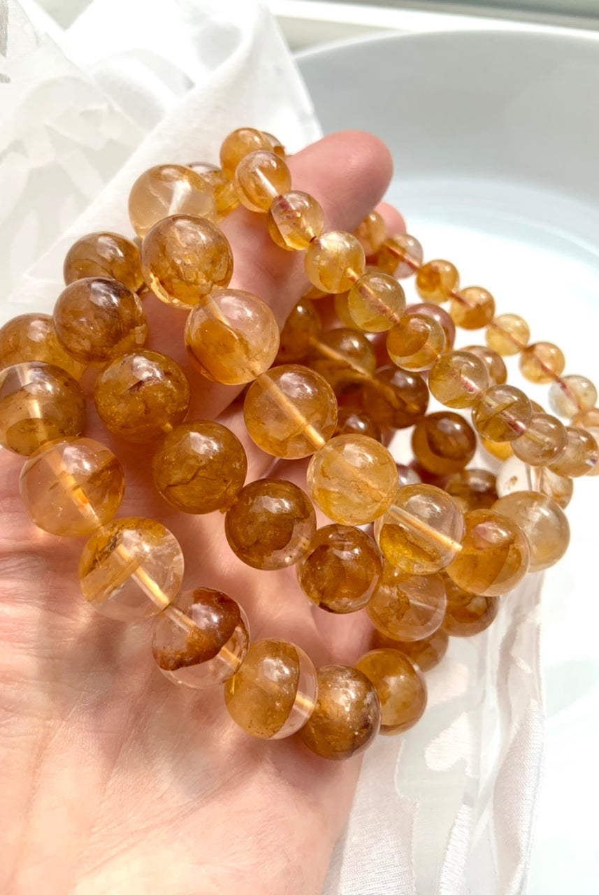 Golden Healer Quartz bracelets held to the light, showing high quality clarity and radiant yellow hematoid inclusions