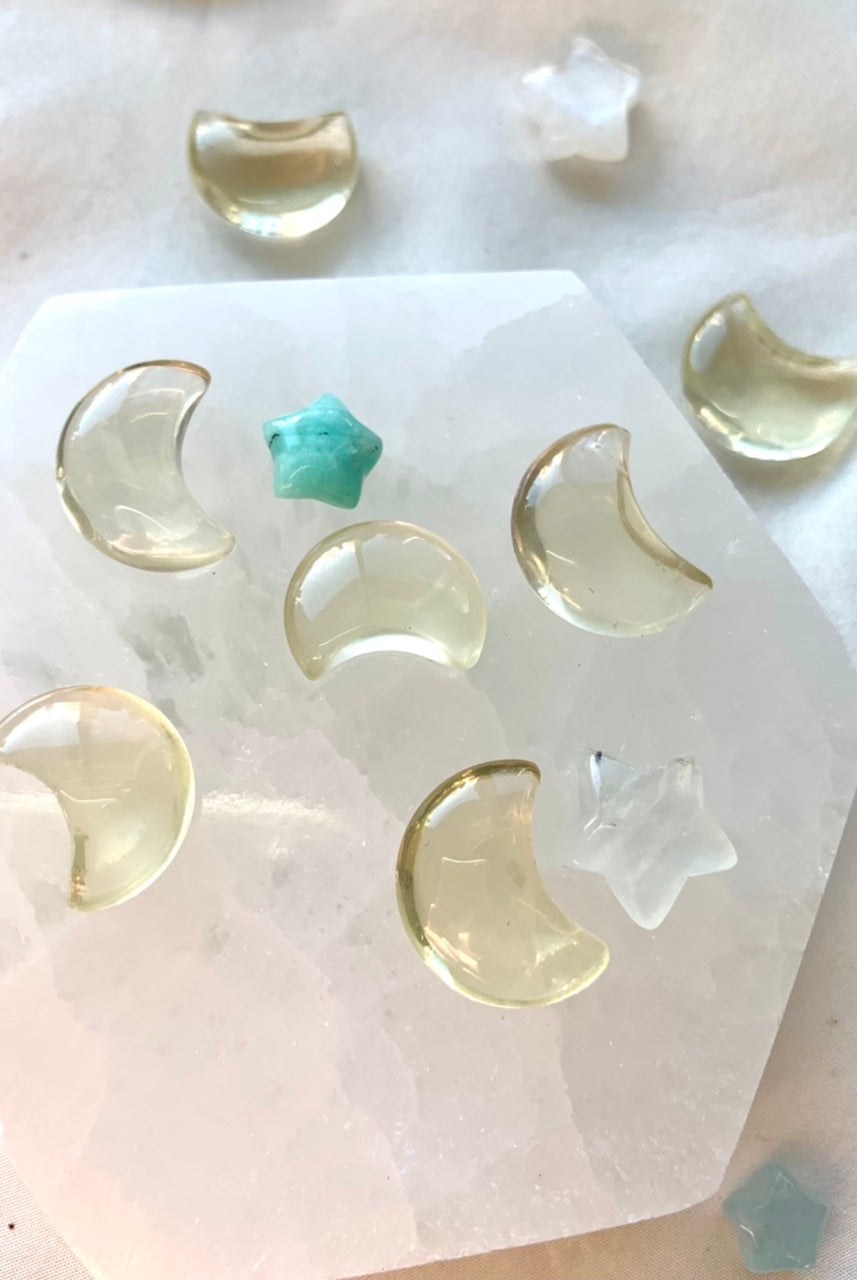 Citrine moons and crystal stars arranged on a selenite plate — mini citrine carvings for healing rituals and energy work