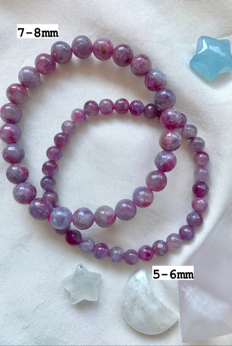 Overhead of 2 Unicorn Stone bracelets on white silk with celestial crystals — marked with 7–8mm and 5–6mm bead sizes, shown with Blue Lace Agate + Aquamarine.