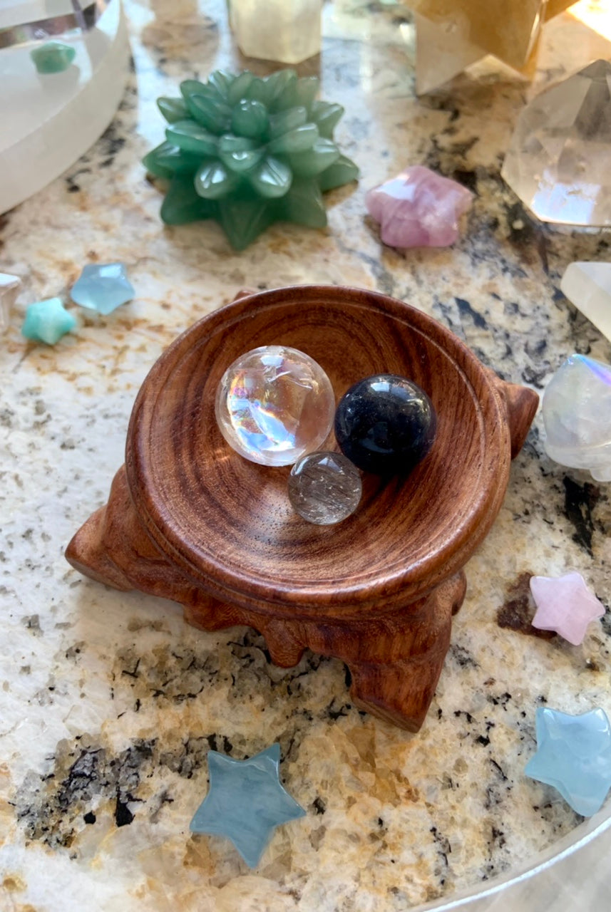 a wooden dish holding a collection of mini crystal spheres