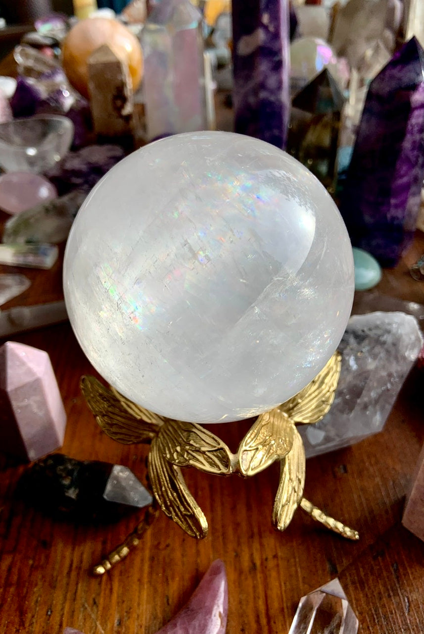 Angled view of gold dragonfly crystal stand displaying an optical calcite sphere in a colorful crystal collection.
