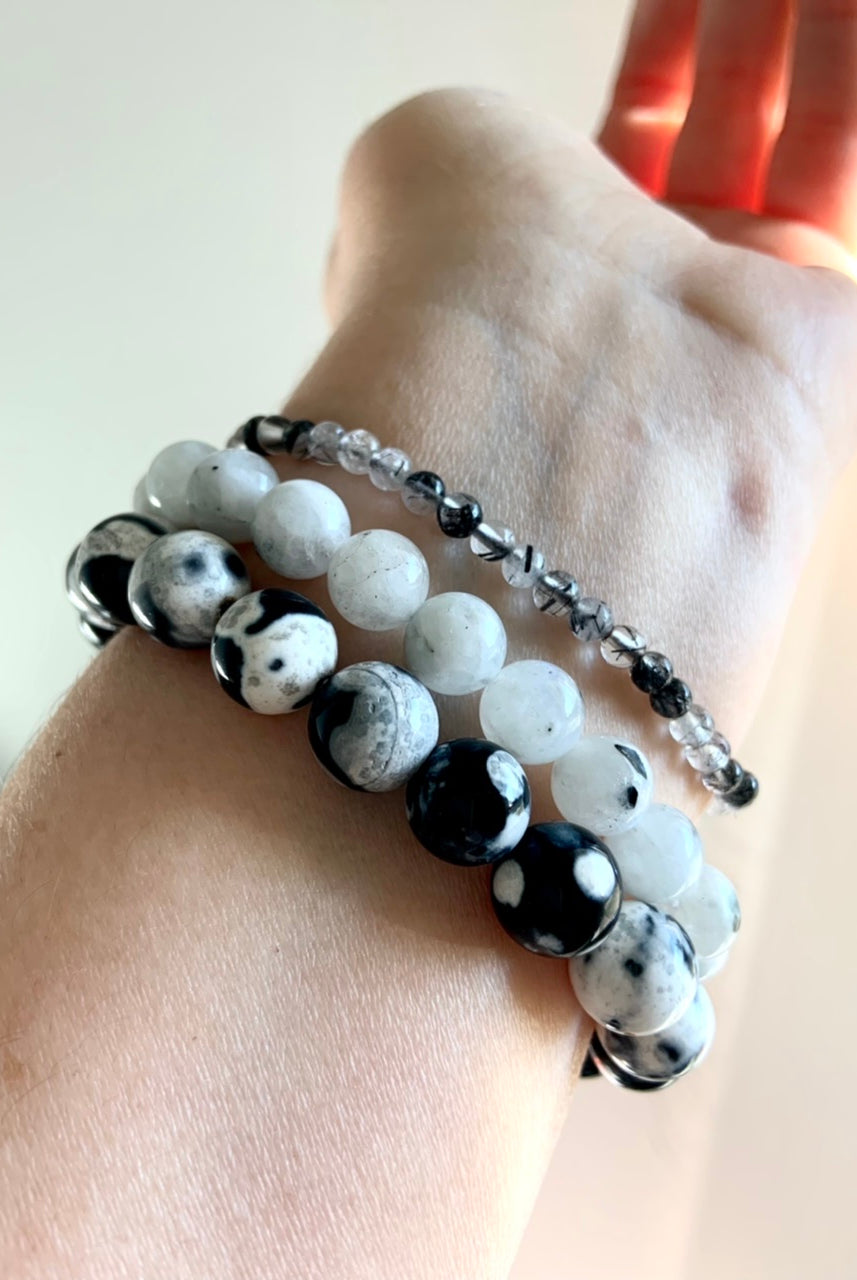 Mixed bracelet stack featuring 10–11mm Orca Agate beads paired with Rainbow Moonstone and Black Tourmaline in Quartz crystal bracelets