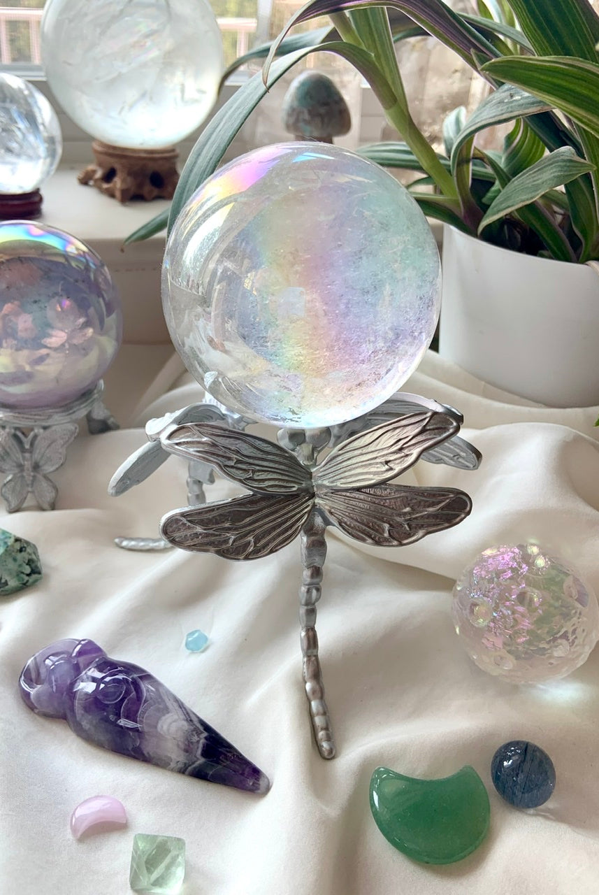 Alternate view of silver dragonfly crystal holder with angel aura quartz sphere and assorted crystals on white silk.