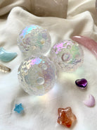 Angled shot of three Angel Aura Full Moon spheres with rose quartz moon, aquamarine moon & amethyst heart — cosmic crystal grid on white silk.