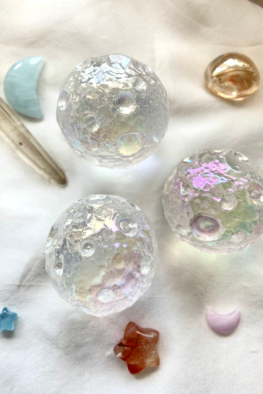 Trio of Angel Aura Full Moon spheres with mini kunzite moon, aquamarine moon & quartz points on white silk — cosmic crystal arrangement for divine energy.