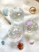 Trio of Angel Aura Full Moon spheres with mini kunzite moon, aquamarine moon & quartz points on white silk — cosmic crystal arrangement for divine energy.