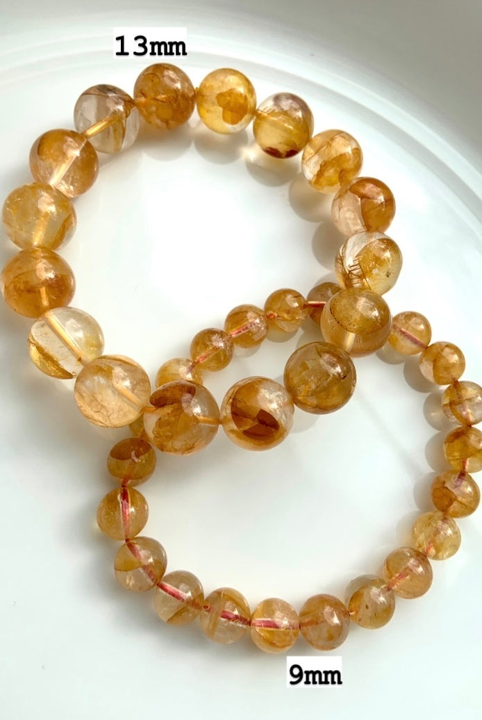 Golden Healer bracelets on a white plate, labeled with 13mm and 9mm bead sizes for comparison