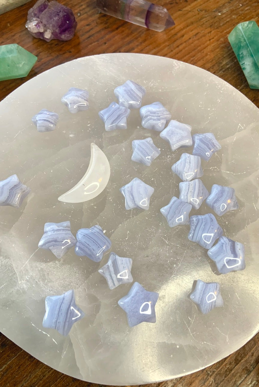 Blue Lace Agate stars displayed on a white selenite plate with a white crystal moon — soothing stones for peace, harmony & throat chakra healing.