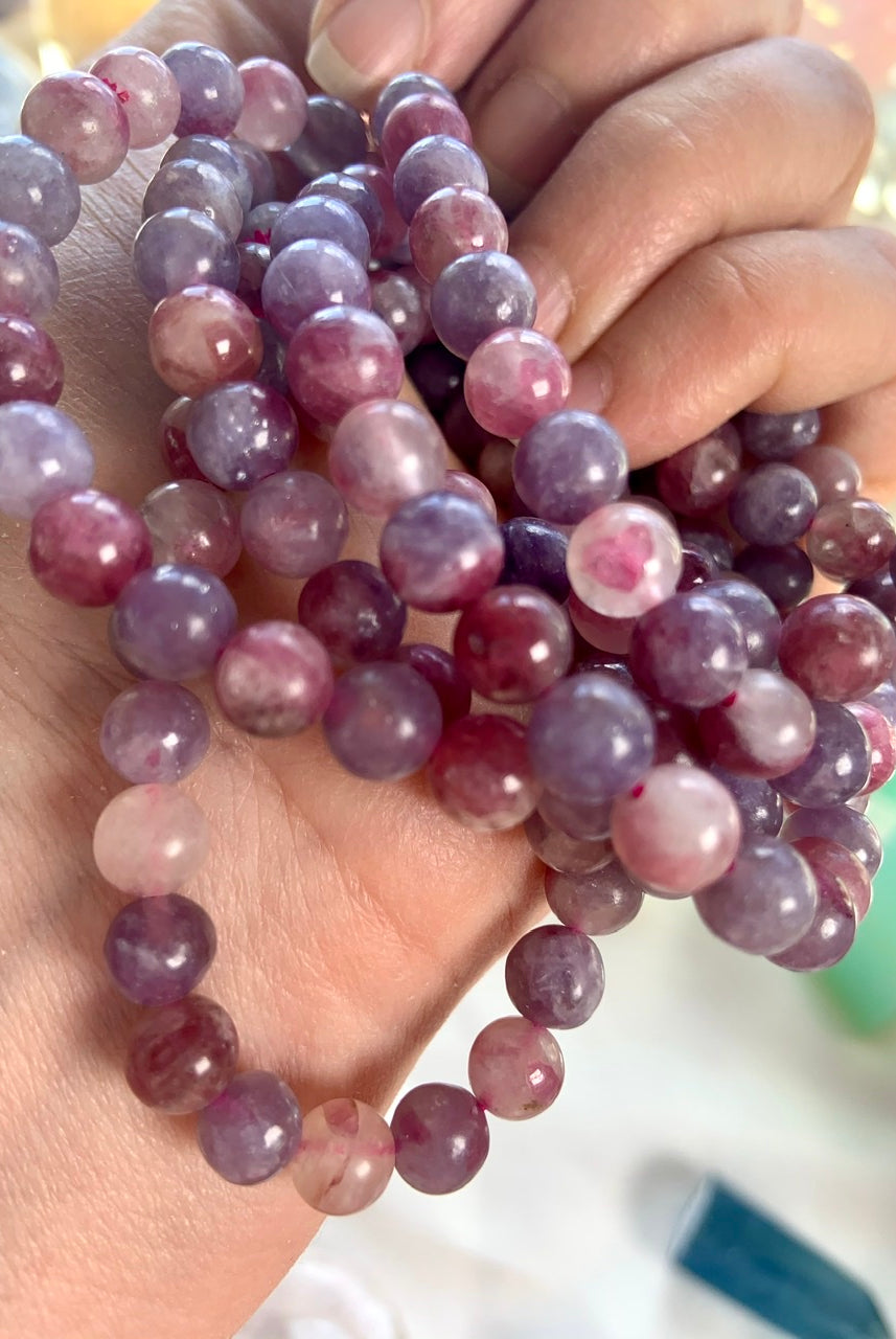Angled view of Unicorn Stone bracelets stacked on a hand — calming pink + purple gemstone bracelets for heart chakra healing and stress relief.