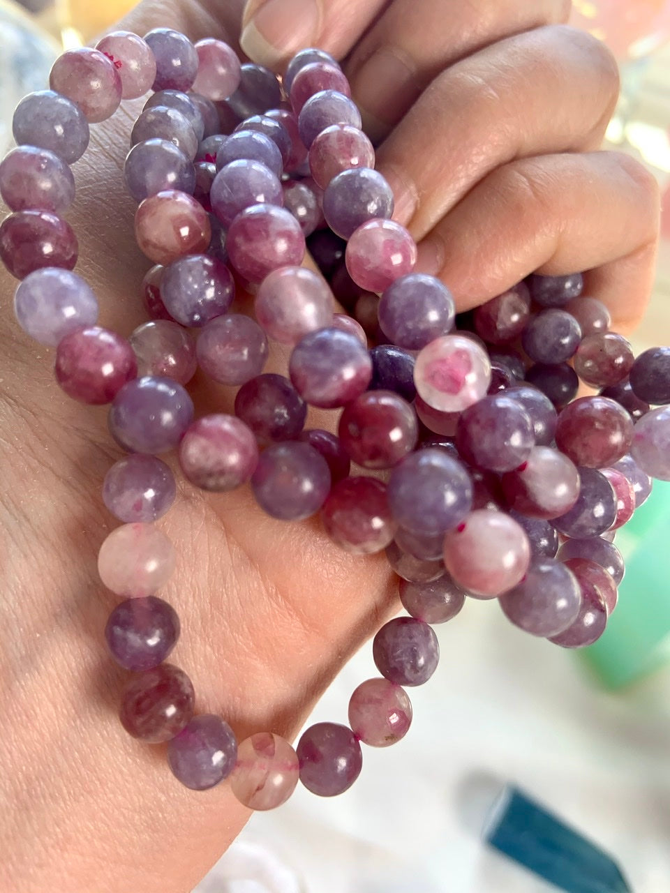 Angled view of Unicorn Stone bracelets stacked on a hand — calming pink + purple gemstone bracelets for heart chakra healing and stress relief.