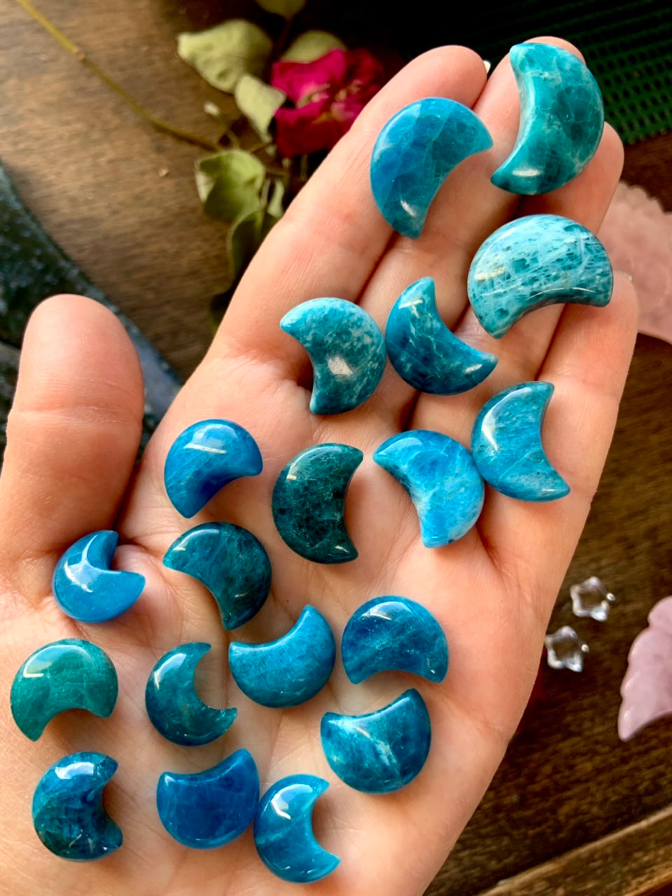 Close-up of Blue Apatite mini moon carvings on hand — teal crystal moons for communication, truth & inspired self-expression.