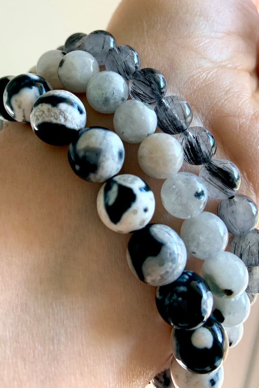 Mixed crystal bracelet stack with Orca Agate, Rainbow Moonstone, and Black Tourmaline in Quartz worn together for layered energy