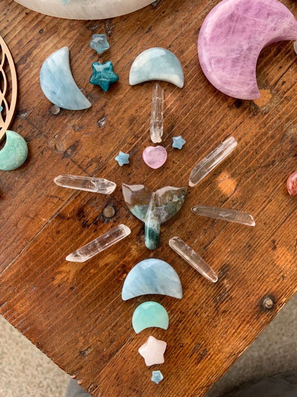 Small clear quartz points styled in crystal grid on wooden table with moon and star crystals for energy work inspiration