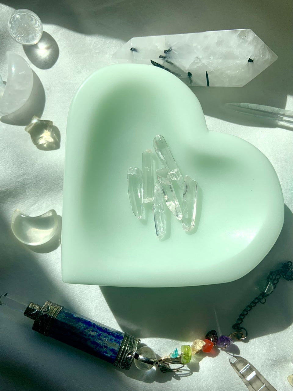 Set of clear quartz points displayed in soft green dish for meditation and sacred decor