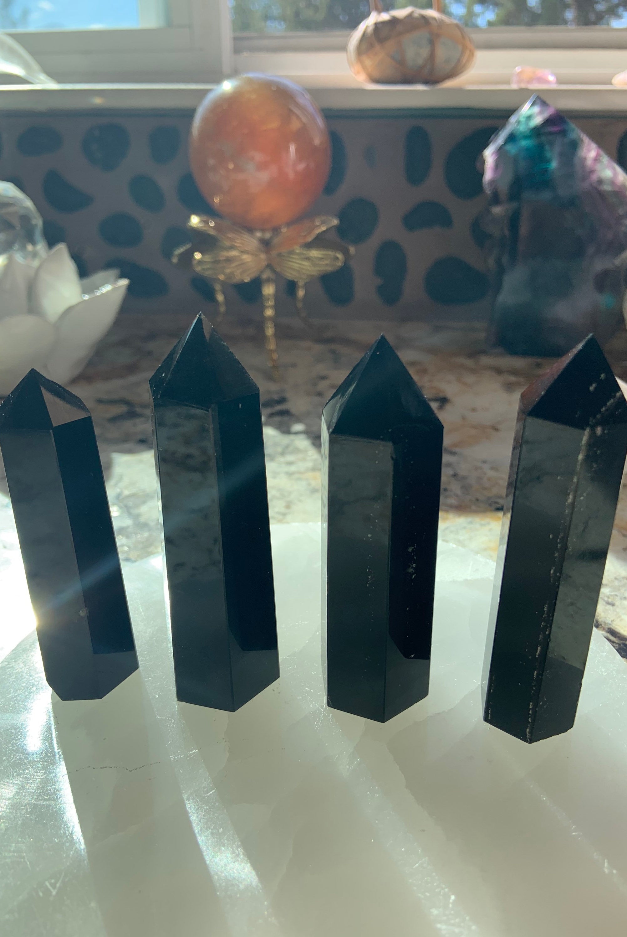 An array of black obsidian points shown in a group on top of a selenite plate