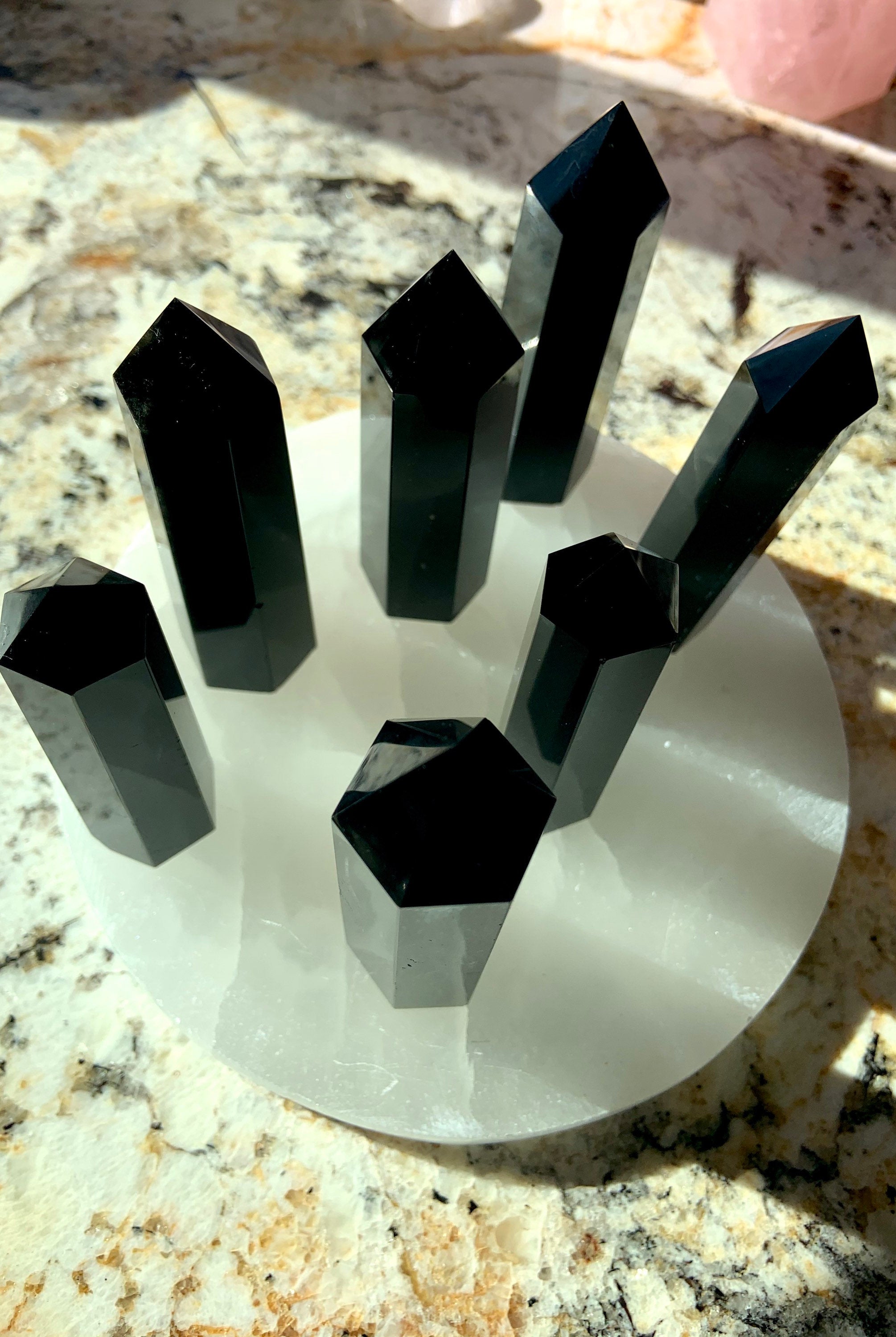 An array of black obsidian points shown from above, on top of a selenite plate