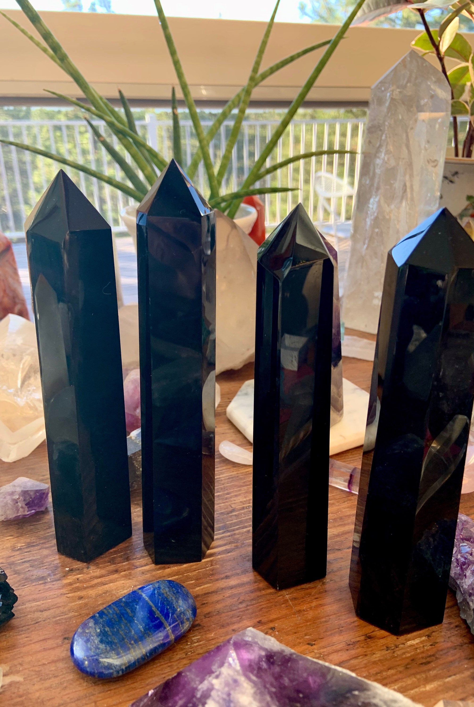 Row of four large Black Obsidian towers on a wooden table — grounding crystals for protection & energetic boundaries.