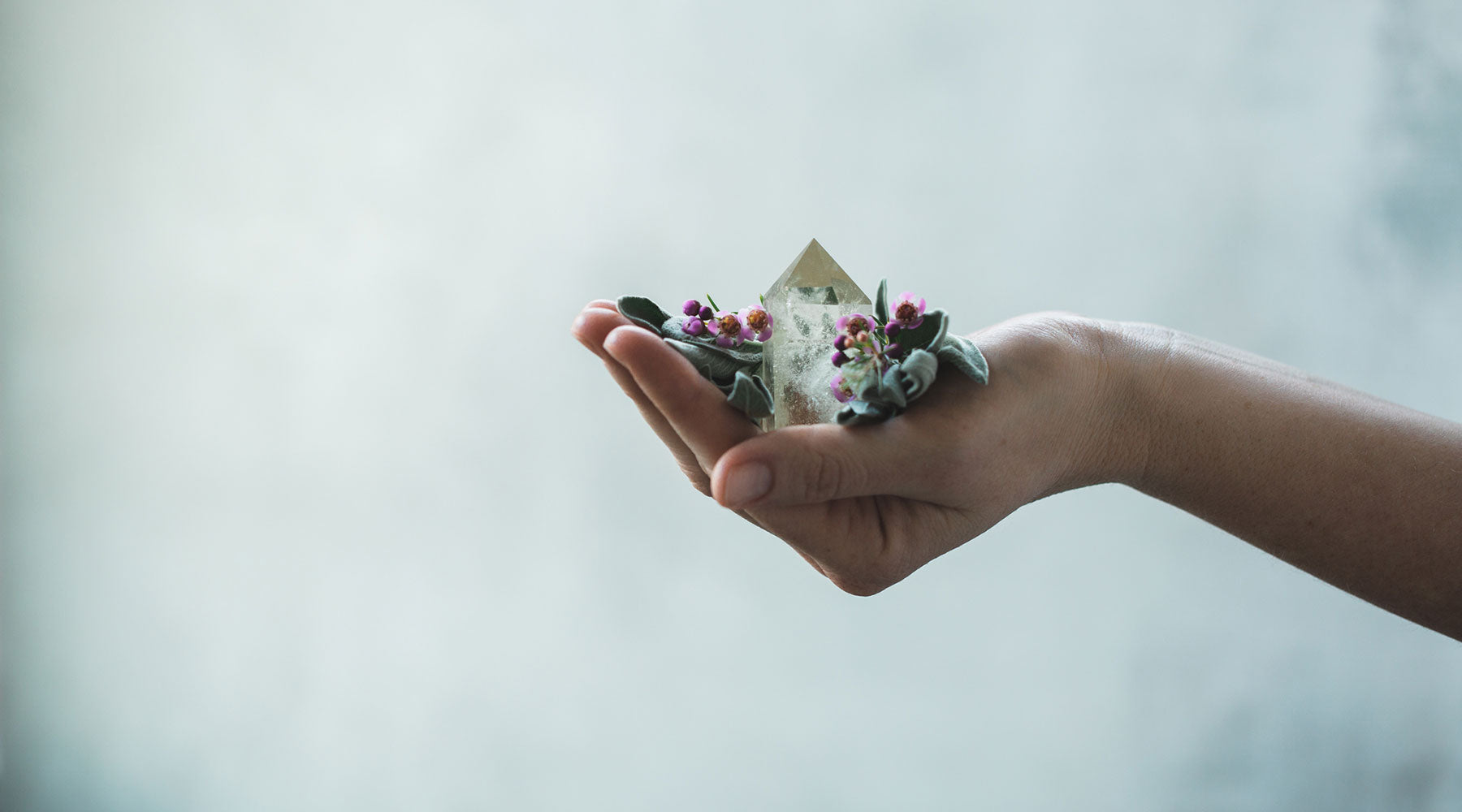 Crystal tower held in hand with flowers – symbol of healing, spiritual energy, and the magic of crystal shapes