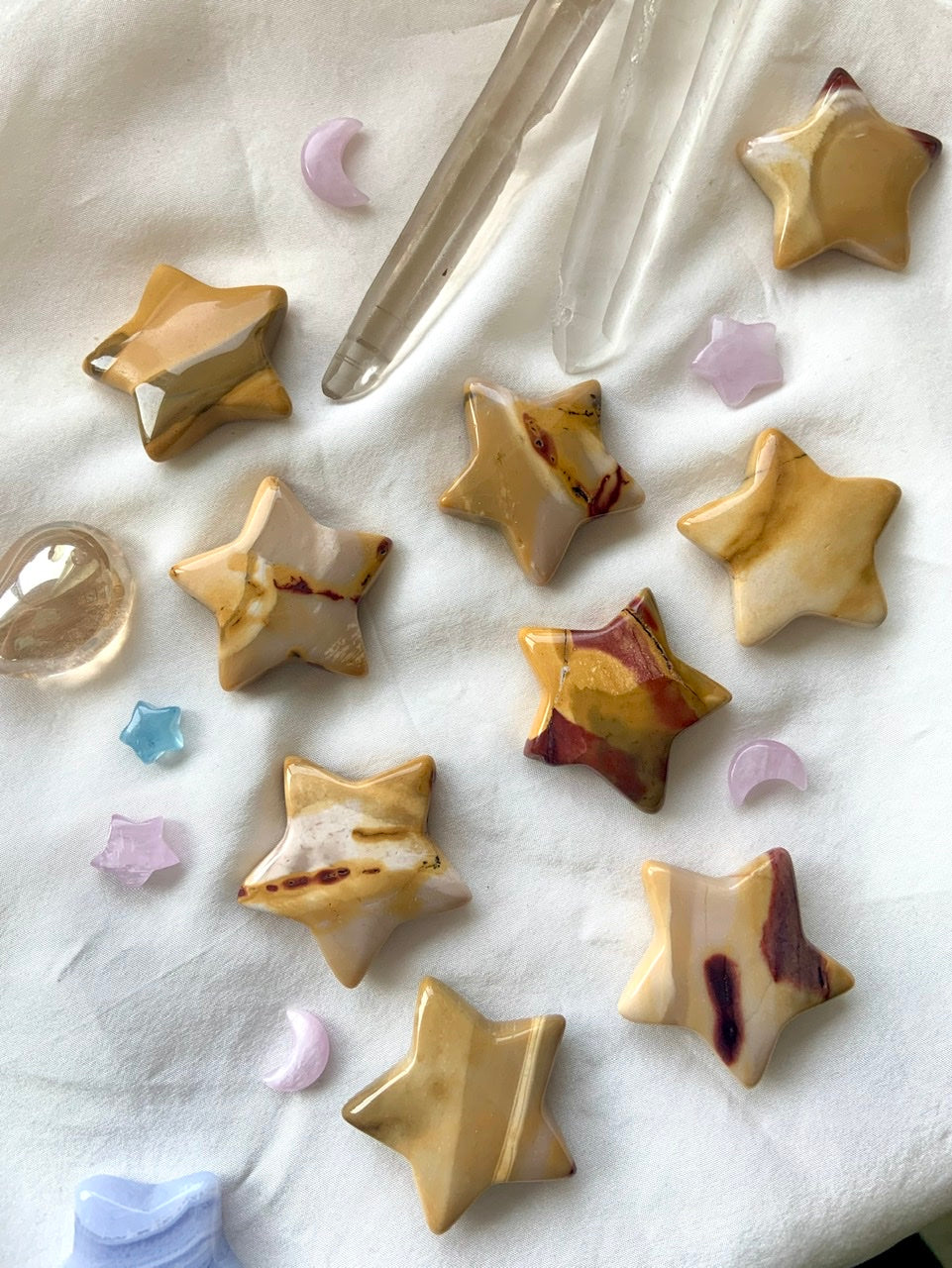 Yellow Mookaite Jasper star crystal carvings arranged in a celestial array with mini crystals — moons, stars, and planetary shapes in golden earthy tones.