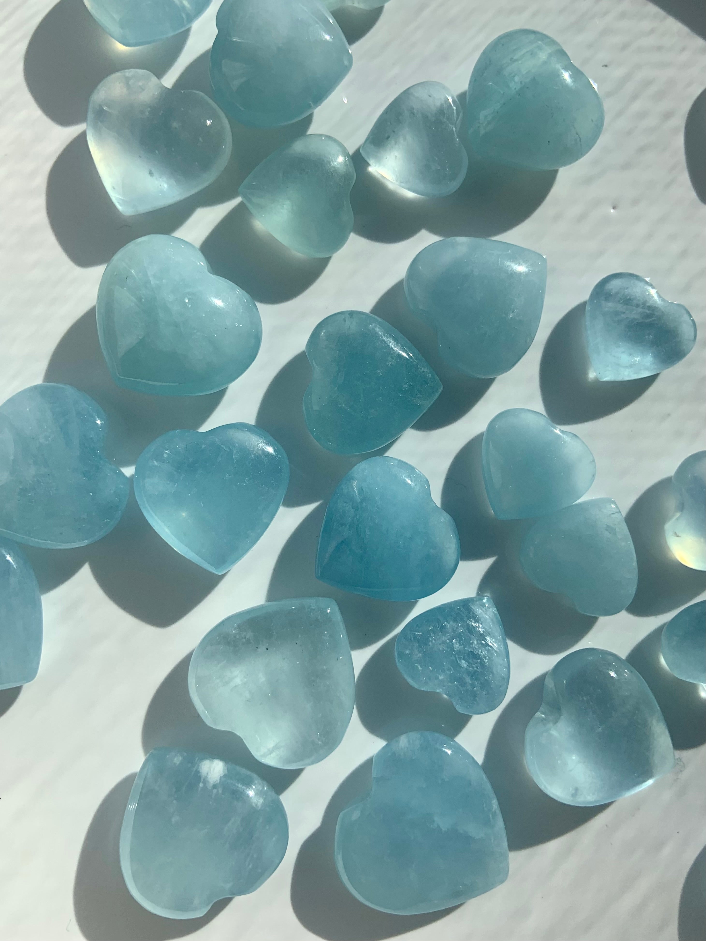 an array of gemmy aquamarine crystal hearts on a white background