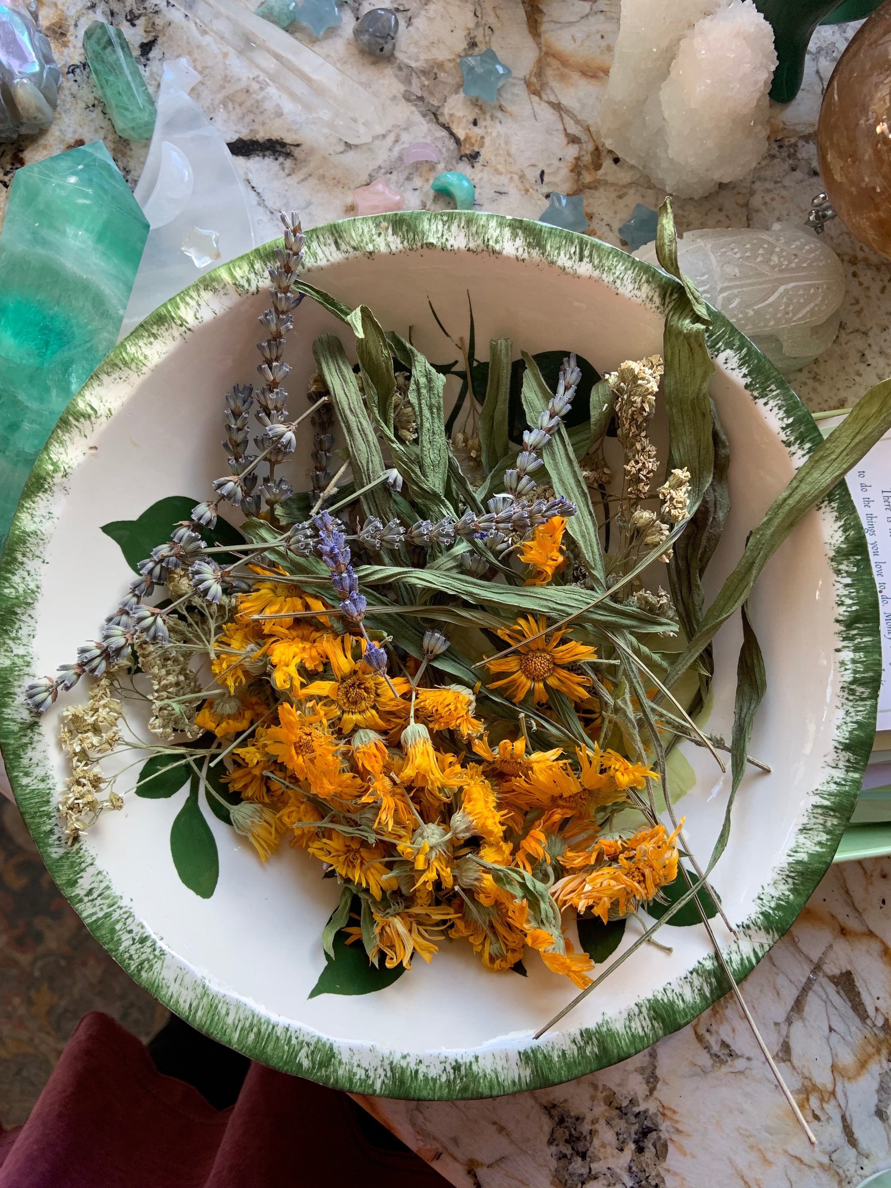 Bowl of dried calendula, lavender, yarrow, and plantain herbs — natural ingredients in SpaGoddess Apothecary skincare.