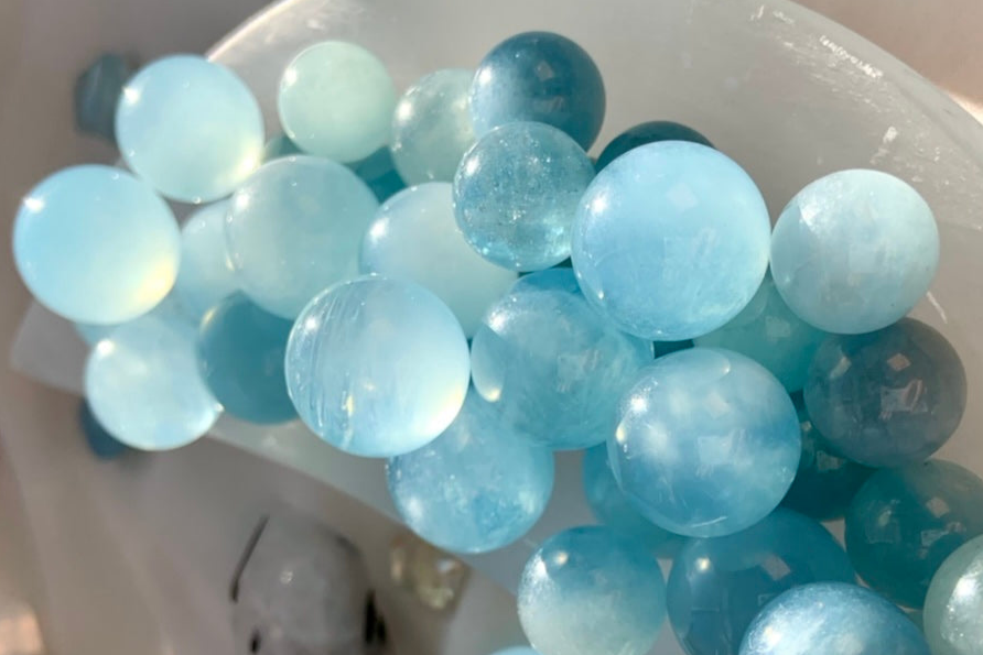 Luminous Aquamarine crystal spheres glowing in soft light — soothing blue Throat Chakra crystals for clarity, communication, and inner calm.
