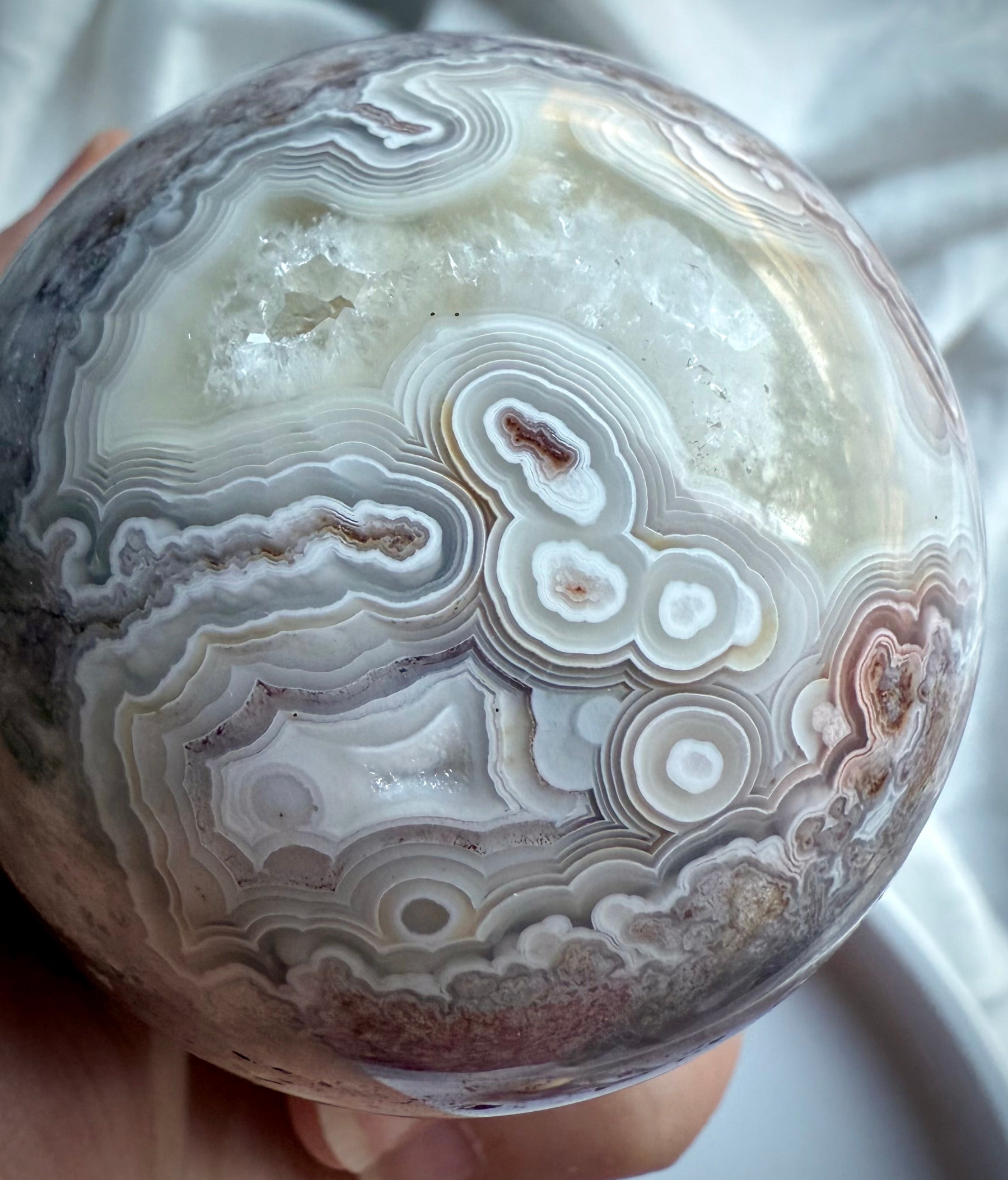Crazy Lace Agate crystal sphere with swirling banded patterns and druzy pocket