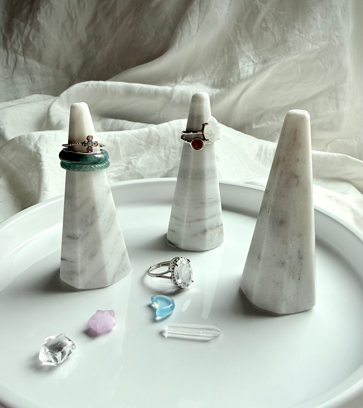 Crystal rings in sterling silver featuring jade and clear quartz gemstone bands styled on marble