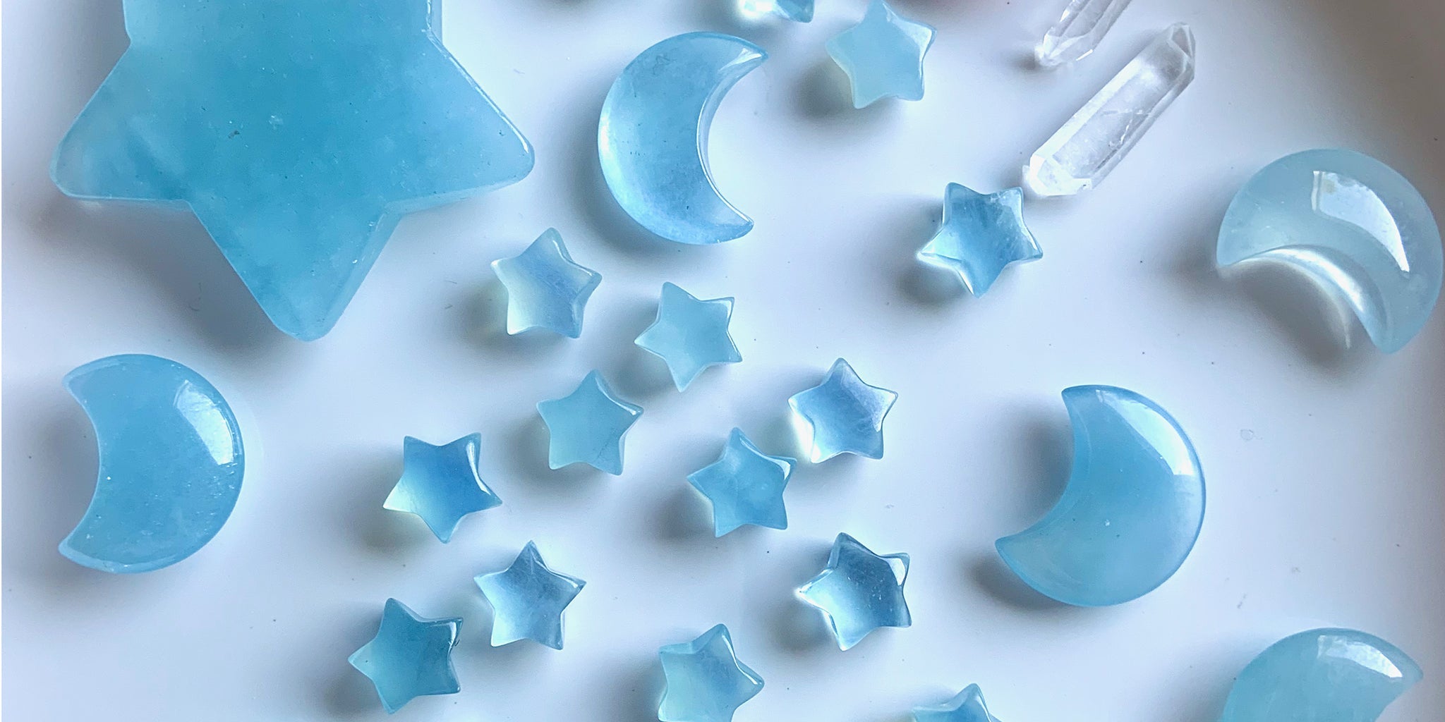 An array of blue aquamarine crystal moons and stars on a white backgrounds