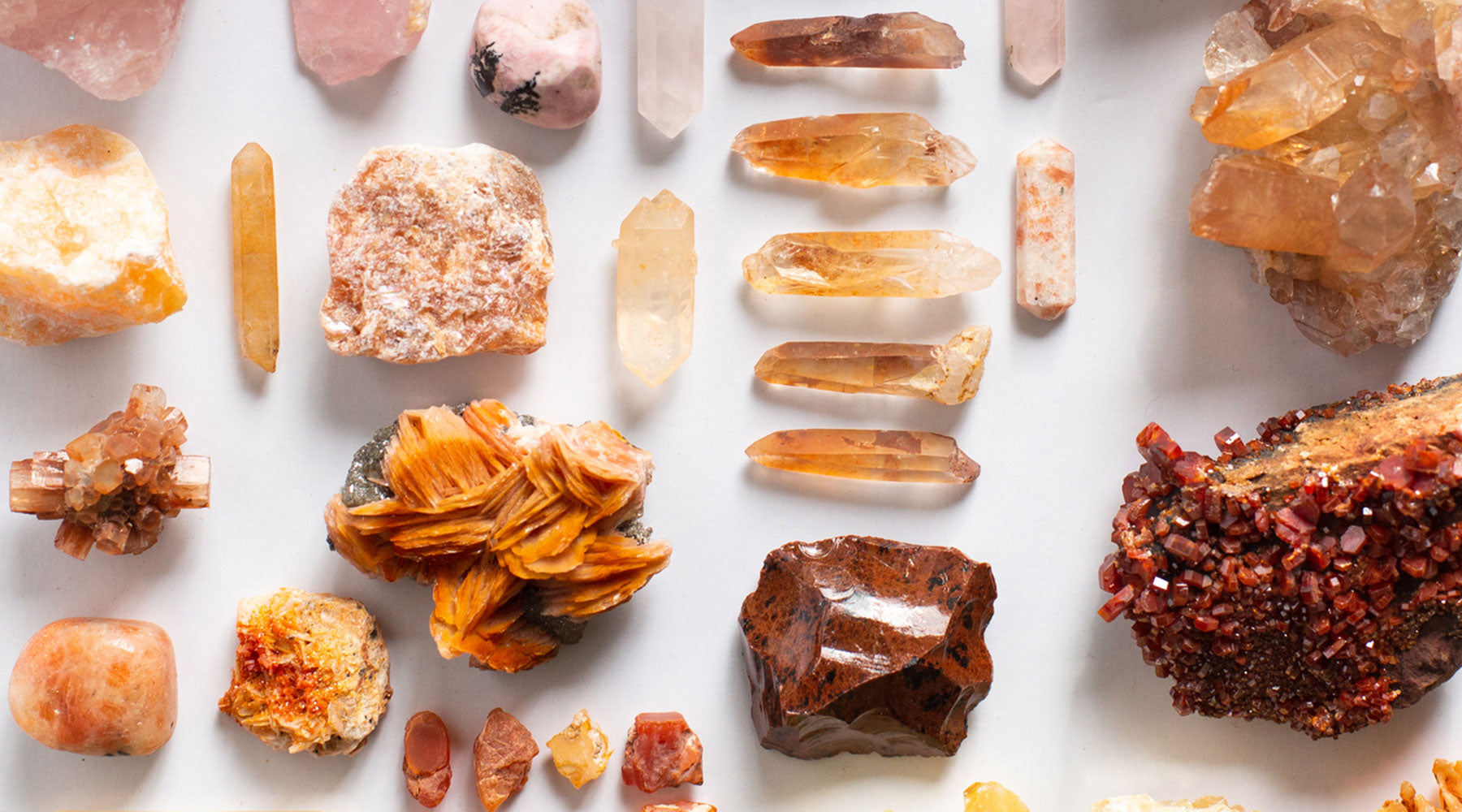 Sacral chakra stones in golden-orange hues — Sunstone, Tangerine Quartz, Orange Calcite, Mahogany Obsidian, Vanadinite, and Aragonite — for creativity, joy, and emotional vitality.