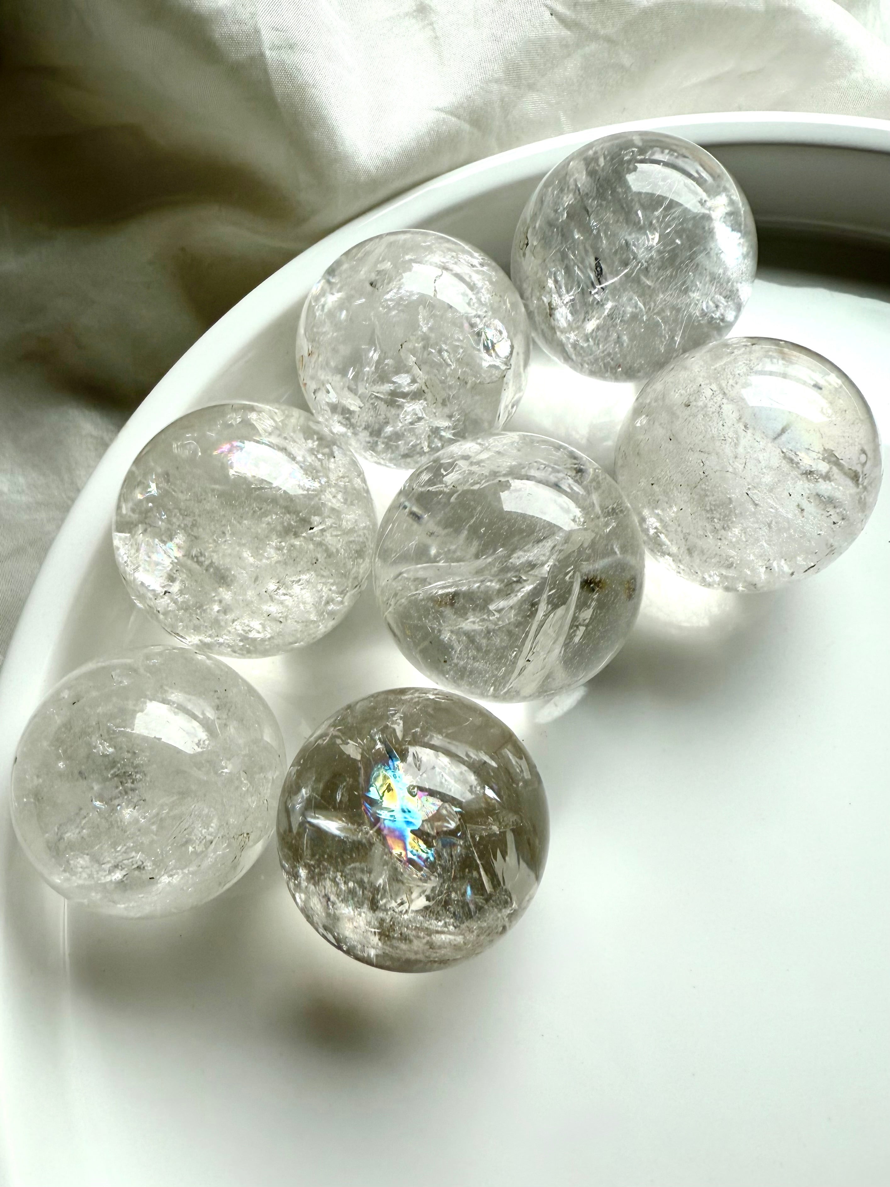 Mini Rainbow Quartz crystal spheres with bright inclusions and clarity in a white dish – healing crystals for energy work and chakra balancing
