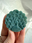 Blue Water Jade peacock medallion up close, showing detailed carving work in natural Guatemalan jade