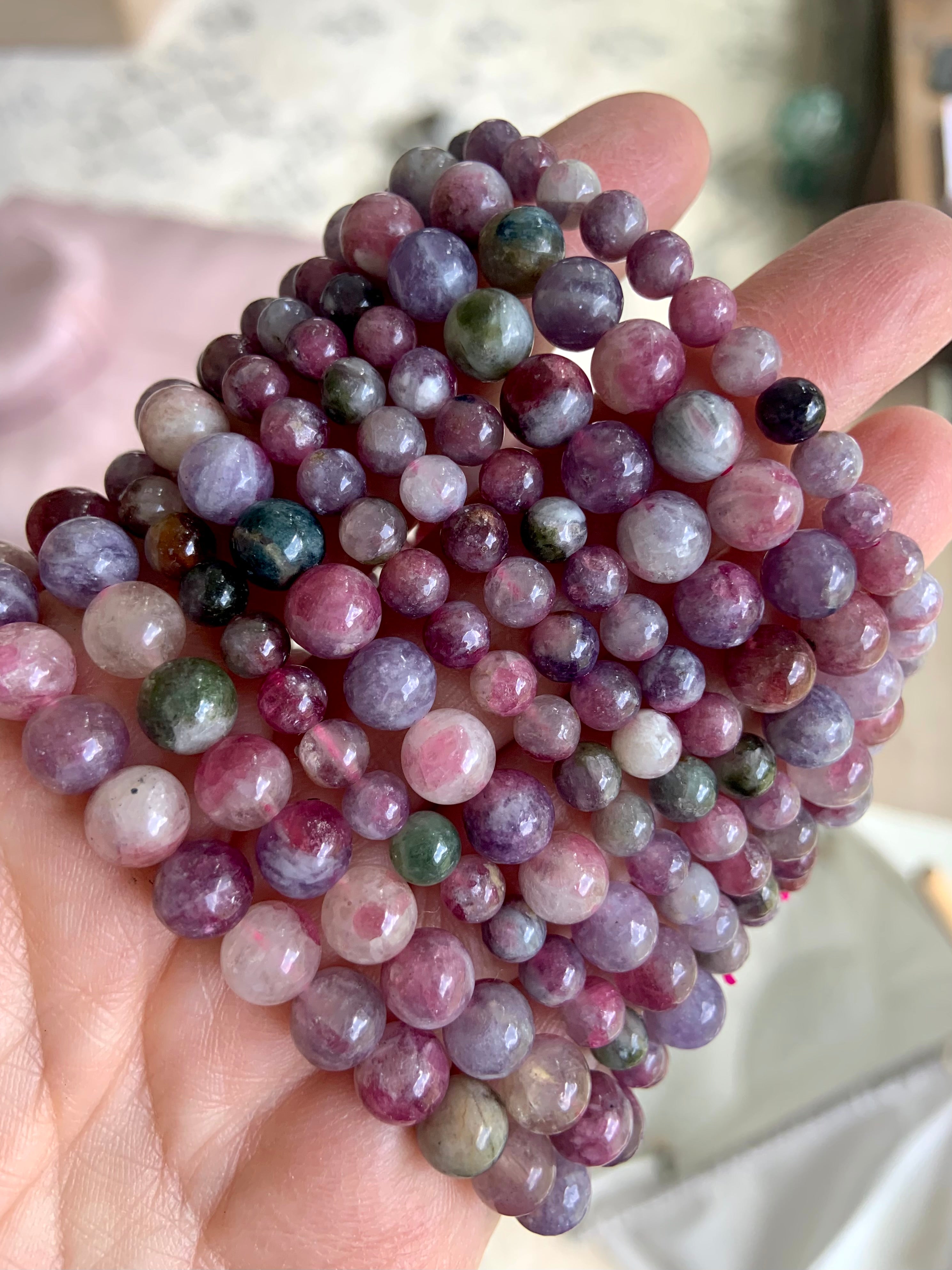 Closeup of stacked Watermelon Tourmaline and Lepidolite bracelets — vibrant crystal beads in mixed sizes for emotional balance + stress relief