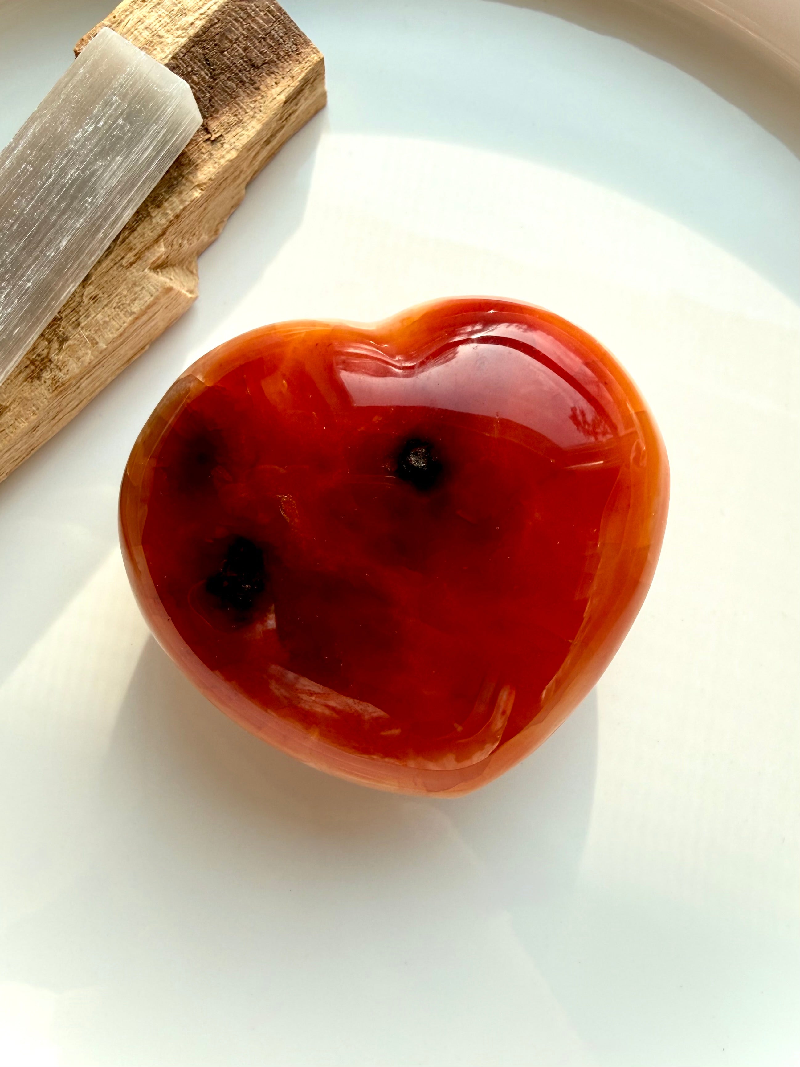 Carnelian heart crystal styled on white with palo santo stick and selenite, Sacral Chakra stone for creative energy, cleansing, and empowerment