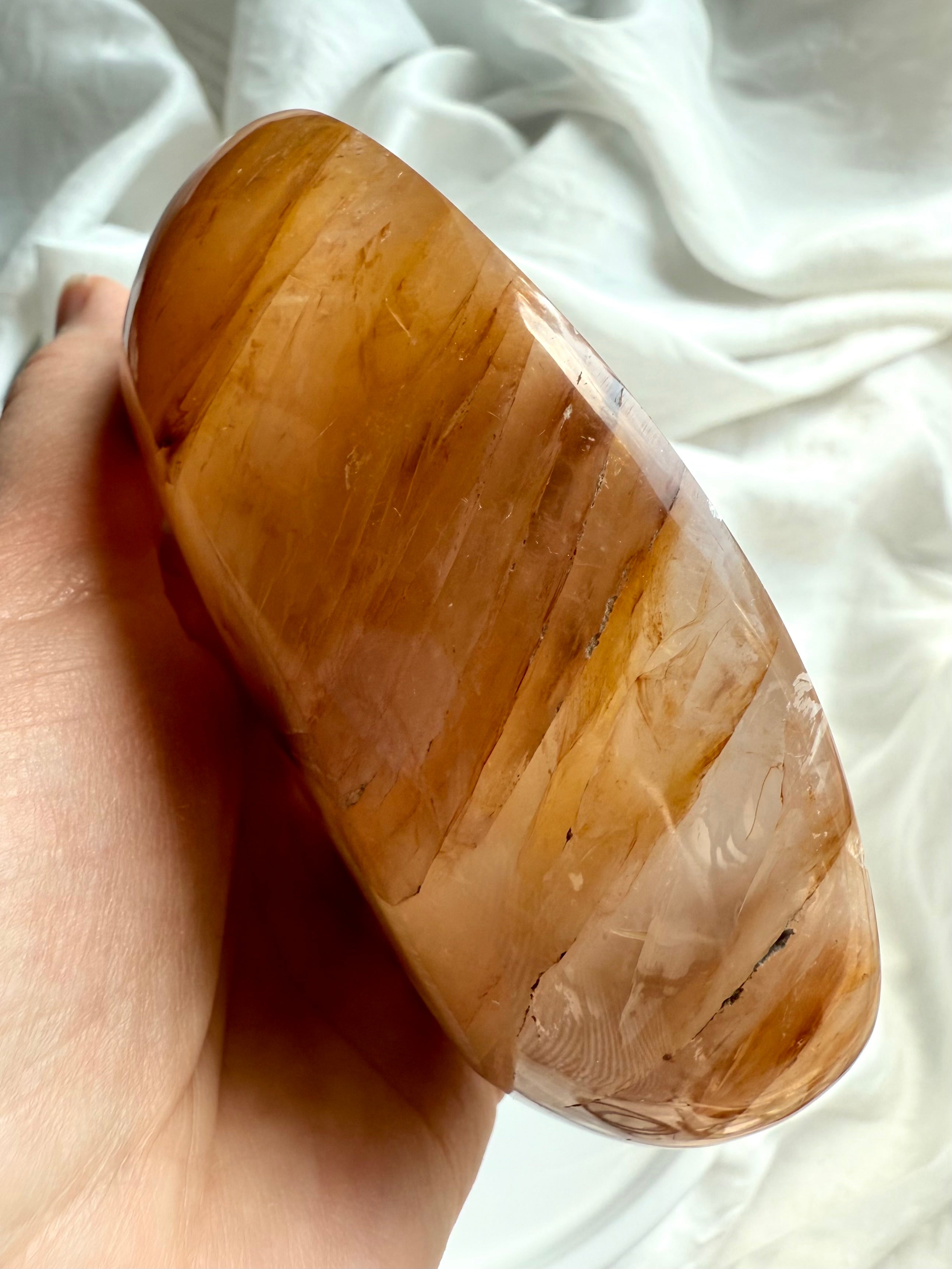 Angled view of polished Golden Healer crystal offering bowl showing depth, glow, and natural stone patterns
