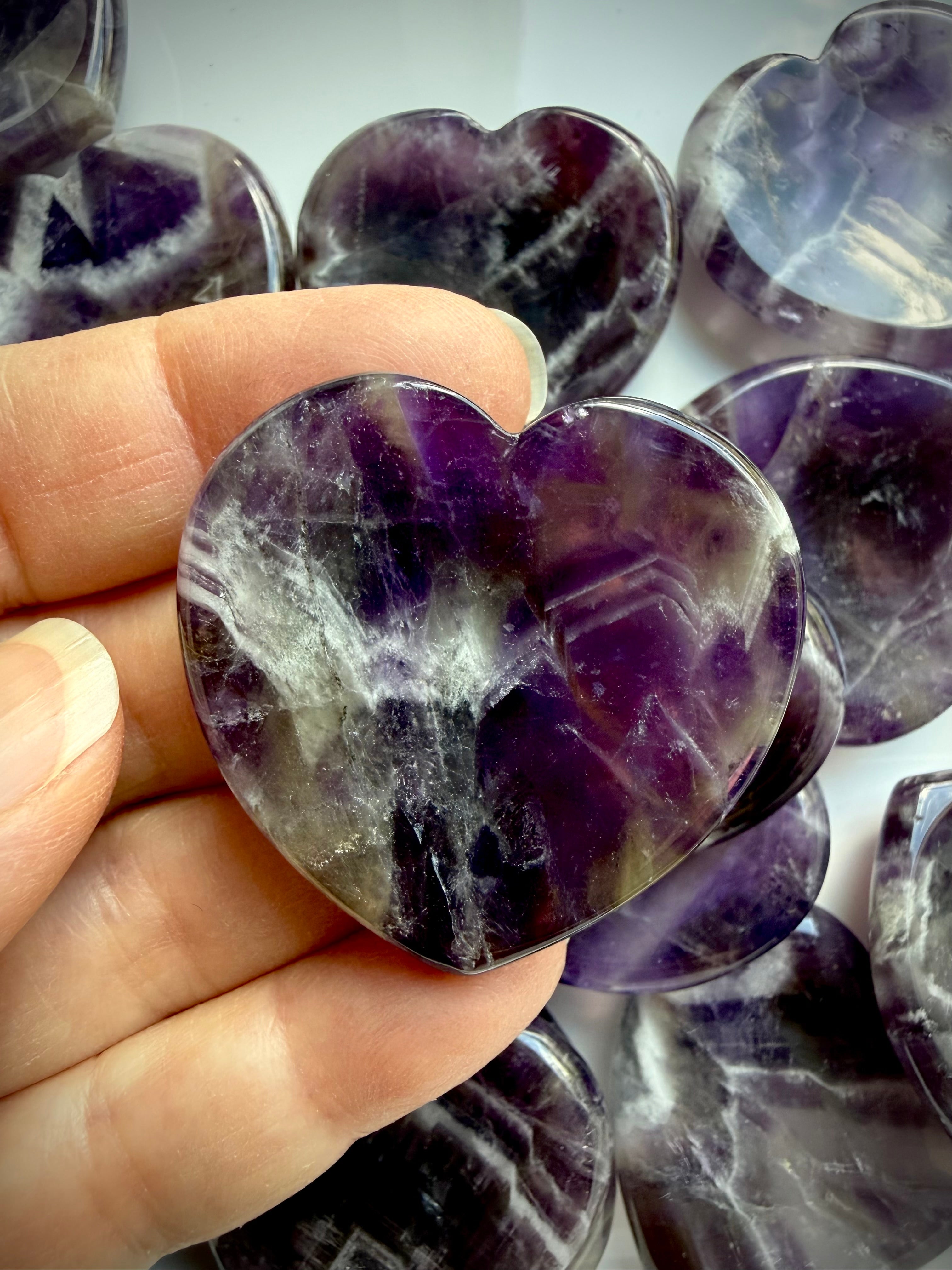 dream amethyst heart stone held in hand showing purple banding for intuition and clarity