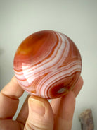 A banded carnelian sphere with swirling contrasting color bands