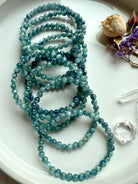 overhead photo of multiple kyanite bracelets on a plate with rich variation of teal, turquoise, and earthy ocean hues