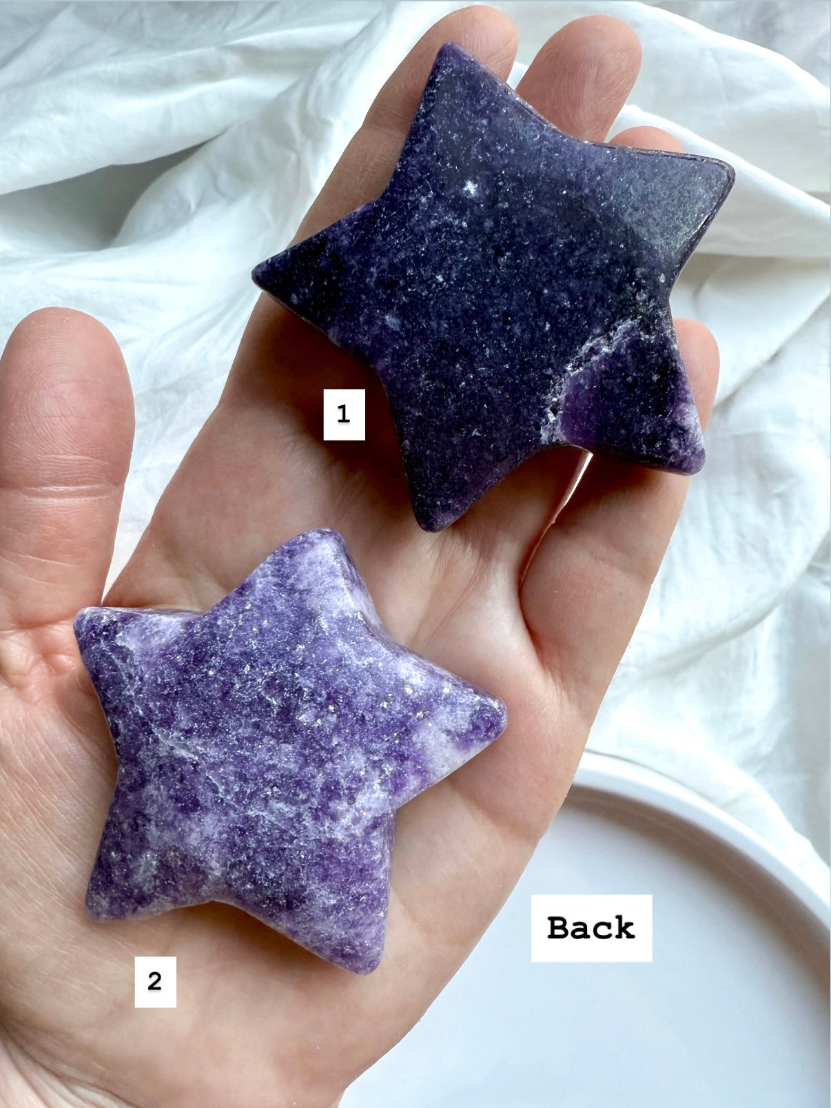 Back view of two numbered Lepidolite star carvings in deep purple with natural variations, smooth polished crystal for chakra balance.
