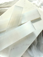 Close-up of polished Selenite charging wands with silky white striations, natural mineral texture and soft pearlescent shimmer