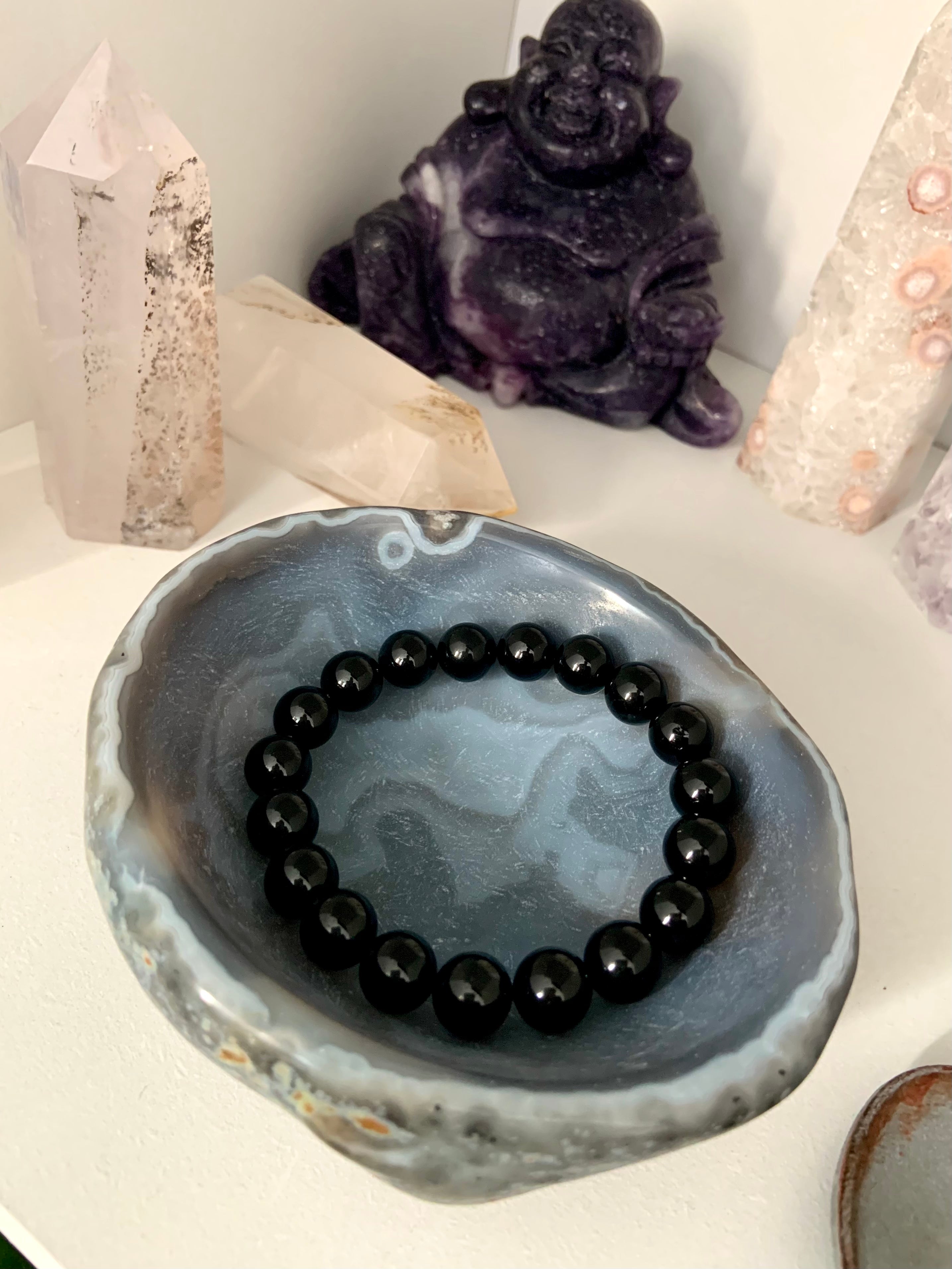 Lifestyle image of a Black Tourmaline bracelet displayed inside a polished agate bowl with other healing crystals — protective crystal jewelry scene