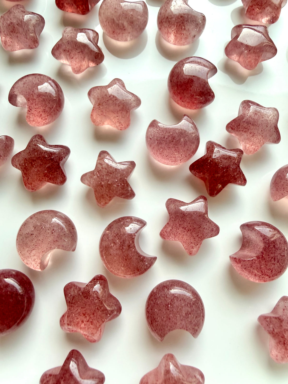 Mini Strawberry Quartz crescent moons and stars displaying translucent pink tones, deep berry red hues and natural crystal patterns