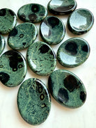 Kambaba Jasper worry stones with naturally varied green, teal, and black patterns, polished grounding stones for meditation