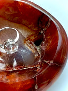 Closeup of a carnelian bowl showing vibrant colors, natural crack patterns, and a druzy cavern 