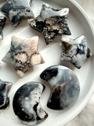 assortment of black flower agate moon and star crystals arranged together highlighting unique natural patterning