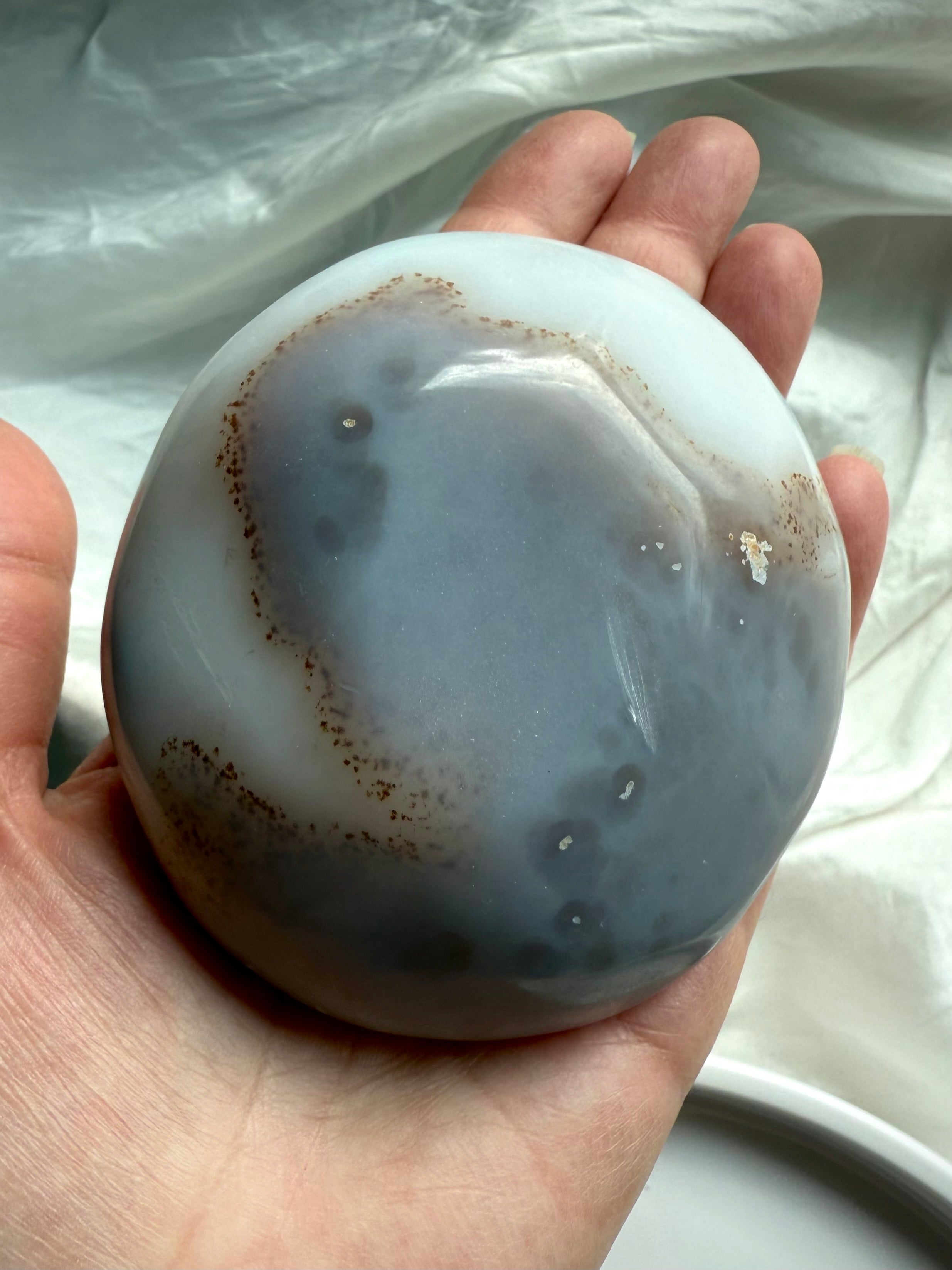 Polished White Agate bowl bottom view in hand – natural crystal carving for grounding and tranquility