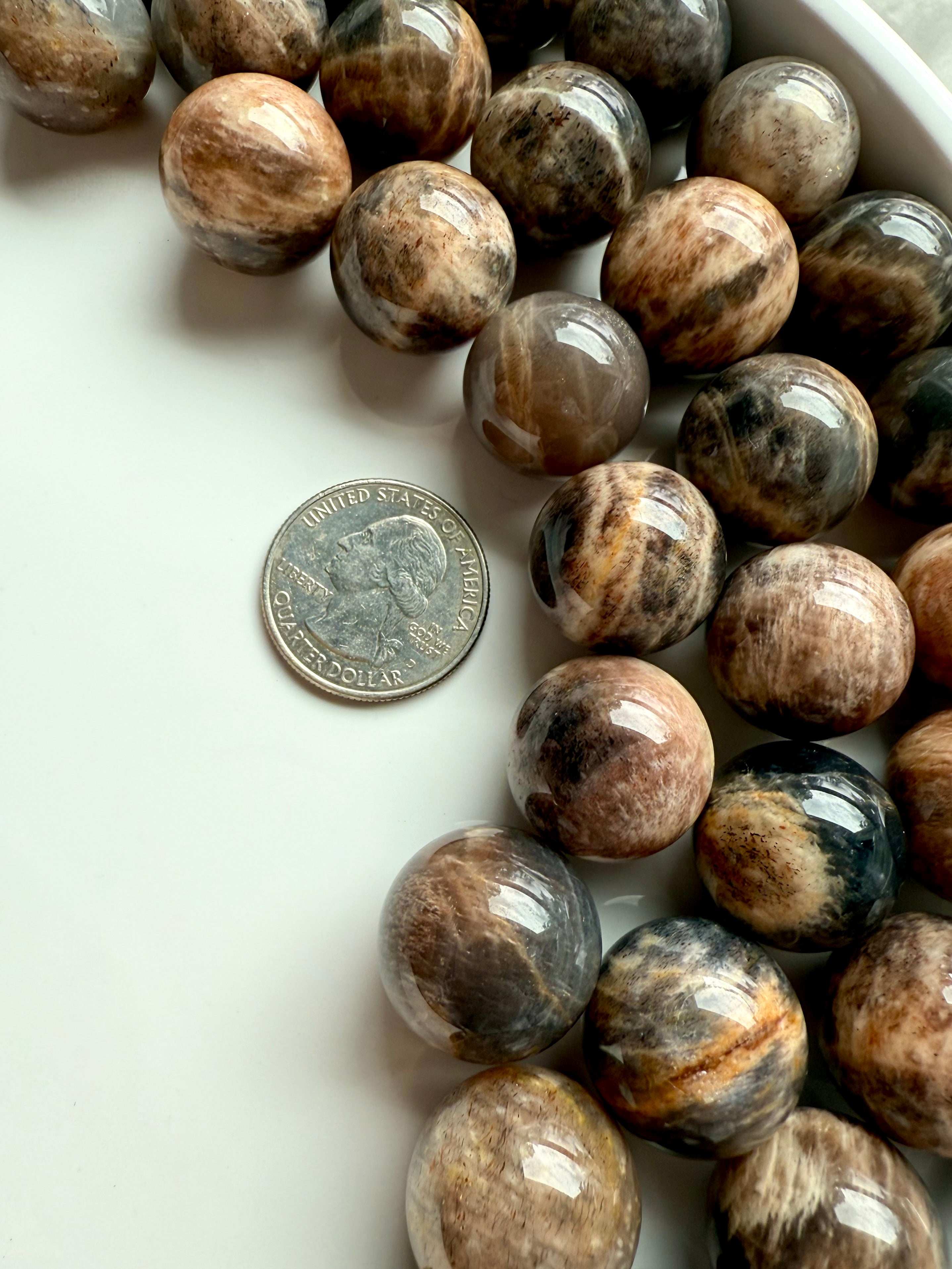 Mini Black Moonstone spheres shown with a quarter for scale, metaphysical properties for intuition & grounding